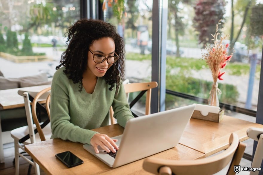 How to make money online: a female freelancer happily working on a project through her laptop.