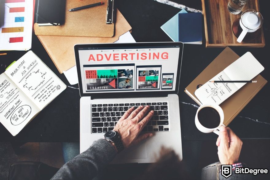 How to make money with AI: A man with cup of coffee and a laptop with advertising written on it.