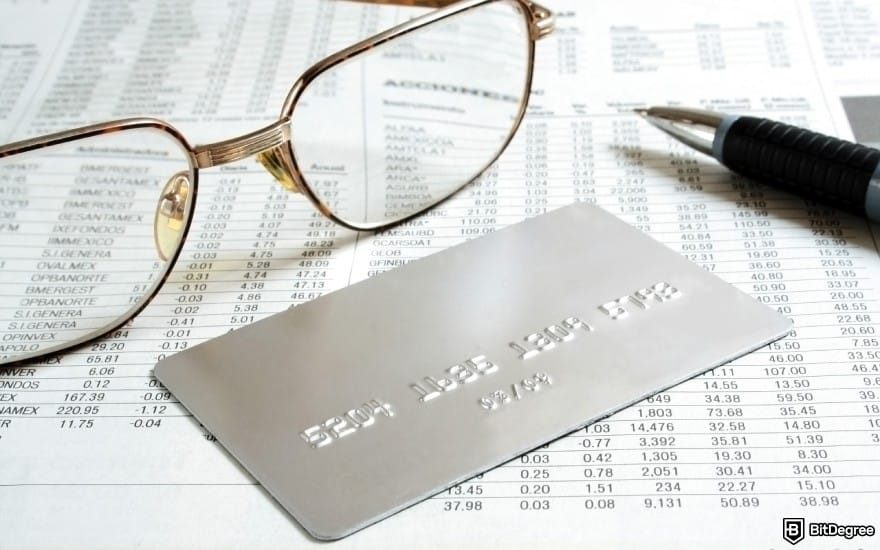 How to open Binance corporate account: a credit card, a pair of glasses, and a pen on top of a ledger.