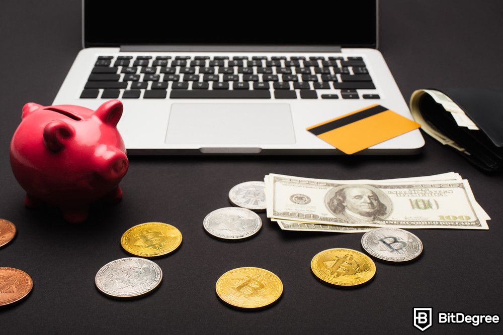 How to pay with Bitcoin: Bitcoins near dollars and laptop on black background.