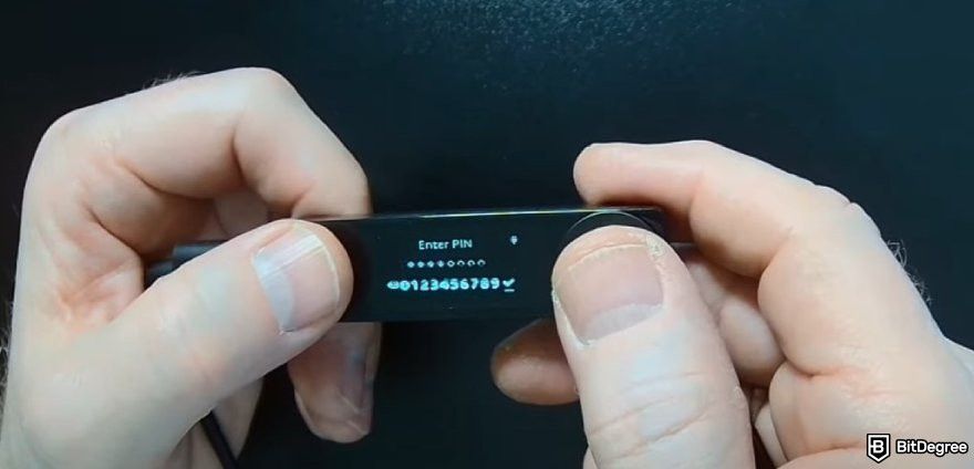 How to recover Ledger: a pair of hands holding a Ledger wallet with the Enter PIN menu displayed.