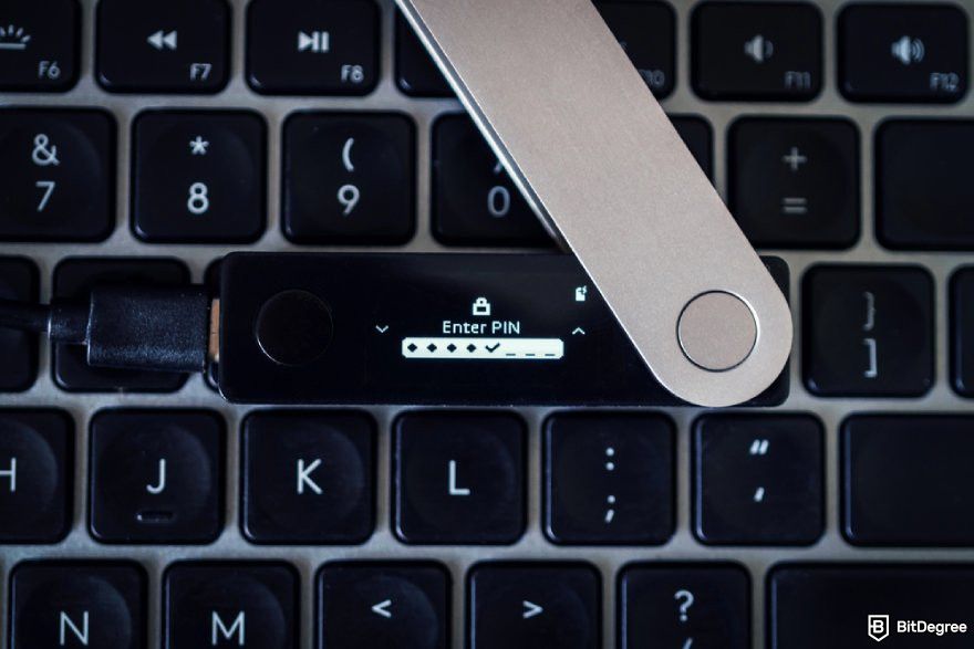 How to recover Ledger: A Legder Nano X on a laptop keyboard with the Enter PIN interface displayed.