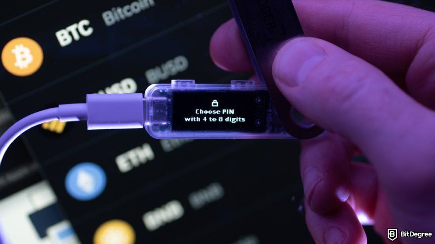 How to recover Ledger: a hand holding a Ledger device connected via USB.