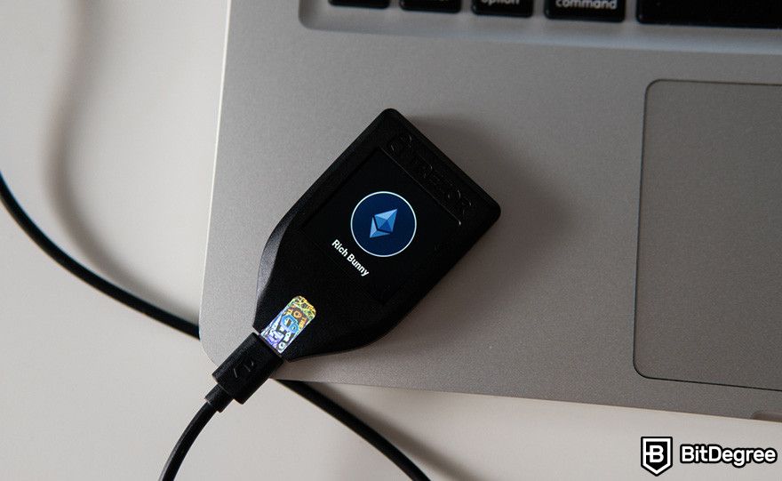 How to sell crypto from cold wallet: a Trezor hardware wallet connected to a laptop via a USB cable.