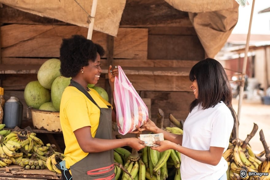 How to send money from Canada to Nigeria: two African women in a market paying with cash in their hands. How to send money from Canada to Nigeria: two African women in a market paying with cash in their hands.