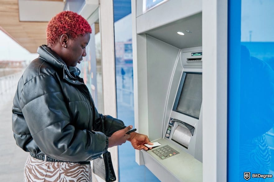 How to send money from India to Nigeria: a person using an ATM.