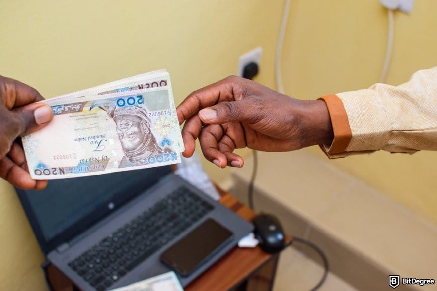 How to send money from India to Nigeria: a hand receiving Nigerian Naira notes.