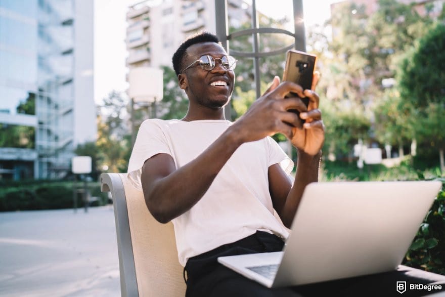 How to send money from India to Nigeria: a person holding a mobile phone cheerfully.