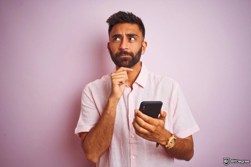 How to send money from India to Nigeria: a person thinking while holding a phone.