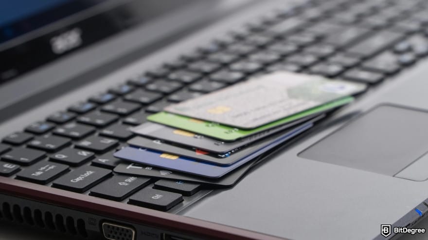How to send money online: a pile of credit cards on top of a laptop keyboard.
