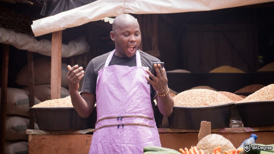 How to send money to Nigeria from USA: a stall owner looking at smart phone.