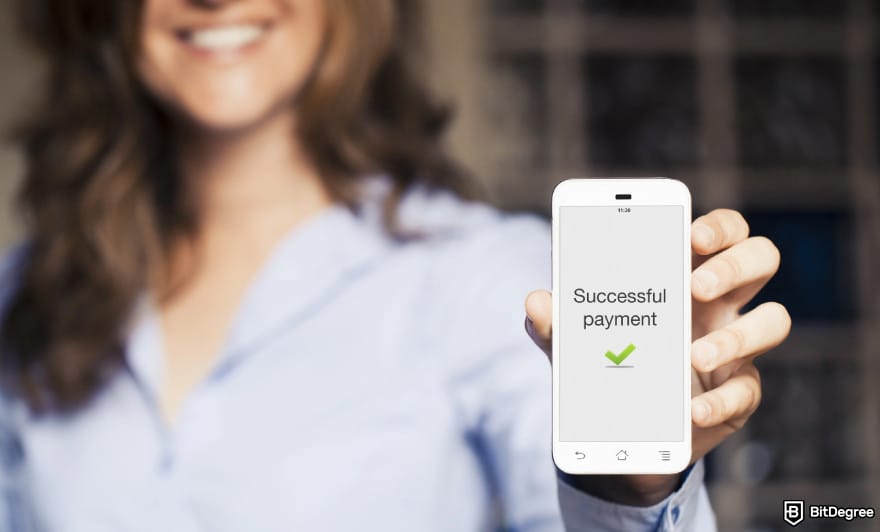 How to send money to someone without a bank account: woman holding a phone showing successful payment to illustrate money transfer.