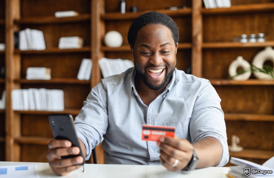 How to send money with debit card: man smiling holding a card to illustrate sending money with a debit card.