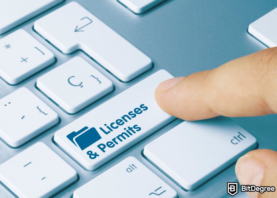 How to start a crypto business: a person pressing a keyboard button that says 'Licenses and permits'.