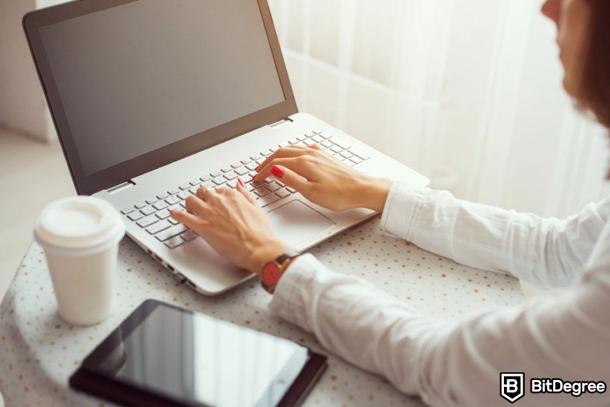 How to start a crypto business: a woman typing on a laptop.