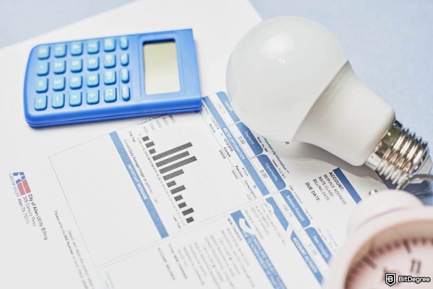 How to transfer money from bank account: a lightbulb and a calculator lying on a utility bill.
