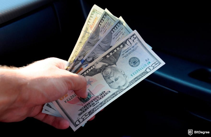 How to transfer money from one bank to another: a hand holding some USD bills.