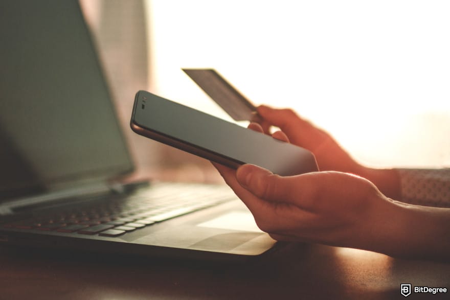How to send money with credit card: a person holding a phone and a card in front of a laptop. How to send money with credit card: a person holding a phone and a card in front of a laptop.