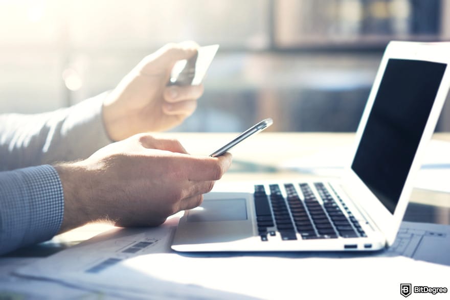 How to send money with credit card: a man using laptop and smartphone while holding a credit card. How to send money with credit card: a man using laptop and smartphone while holding a credit card.