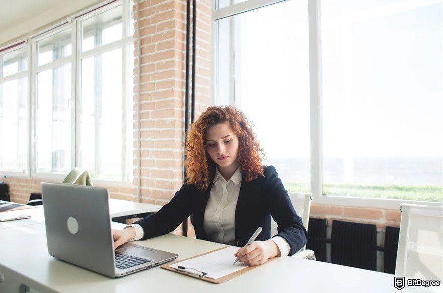 How to use AI for crypto trading: a woman with her laptop and a paper.