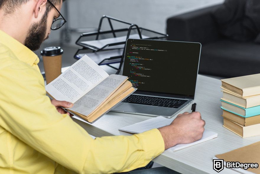 How to use GitHub Copilot: Person reading book, learning to code.