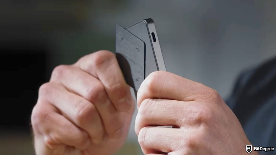 How to use Ledger Recovery Key: a person holds a Ledger device while tapping it with a Recovery Key.