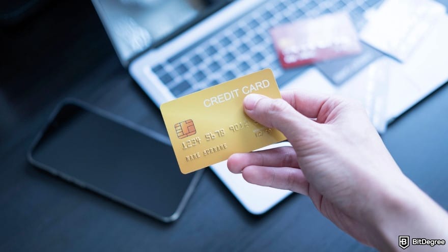 How to withdraw cash from Credit Card: a hand holding a golden physical credit card.