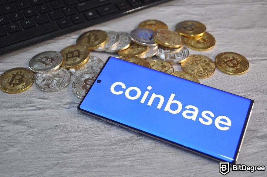 How to withdraw from Coinbase: Coinbase logo on a phone screen amid Bitcoin coins and a keyboard.
