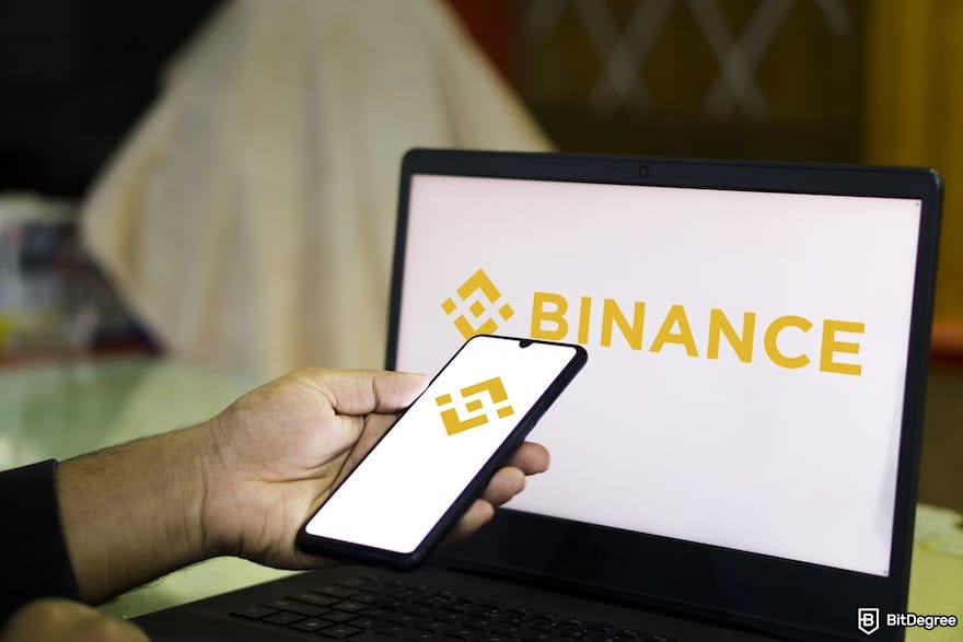 How to withdraw money from Bybit in Nigeria: a person staring at Binance's logo on a phone and a laptop.