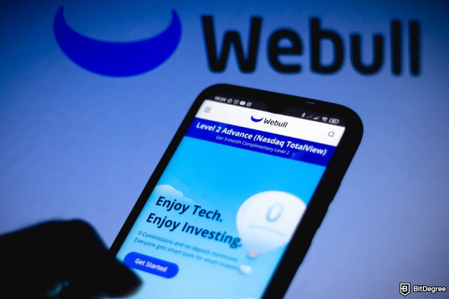 How to withdraw money from Webull: a hand holding a phone displaying Webull mobile interface.