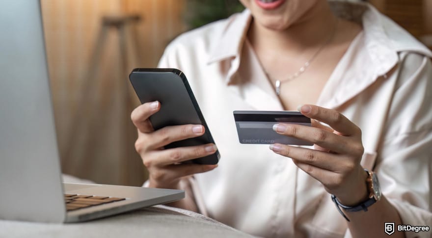 How to withdraw money from Western Union: woman holding phone and card to illustrate Western Union mobile banking transfer.