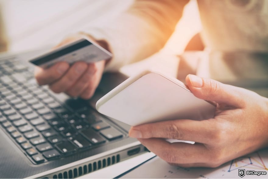 How to withdraw money from Wisely card: a person holding a debit card and a phone, making an online payment. How to withdraw money from Wisely card: a person holding a debit card and a phone, making an online payment.