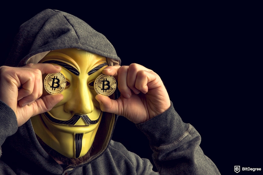 Indodax review: a person wearing a hoodie and a gold anonymous mask while holding BTC coins.