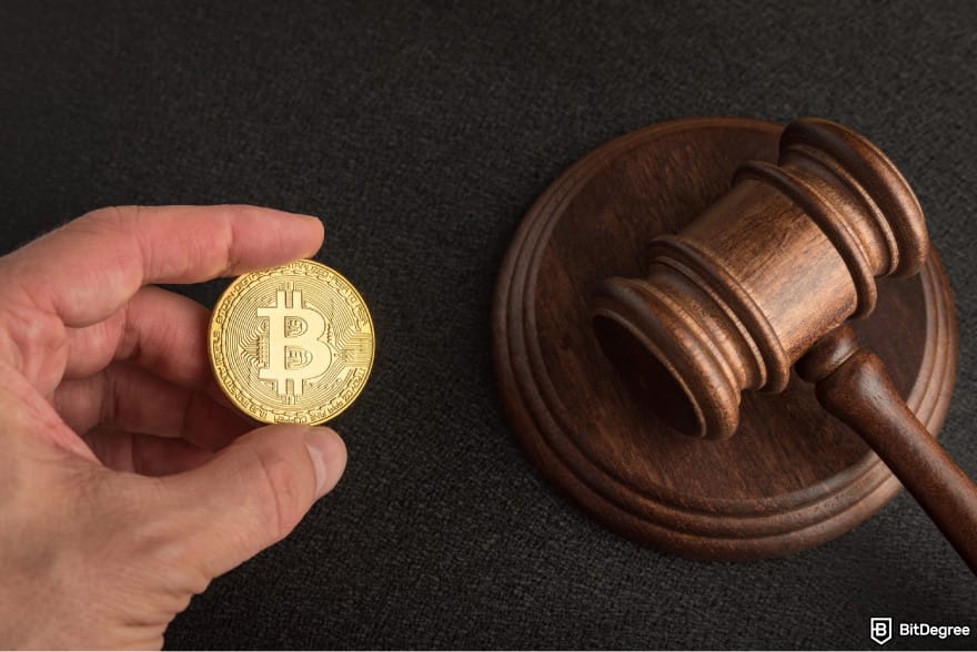 Is Binance safe: a person holding a judge's hammer and a Bitcoin.