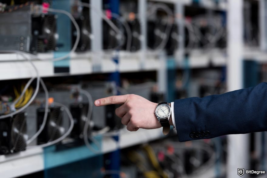 Is Bitcoin legal: a hand with a watch pointing to a crypto mining farm.