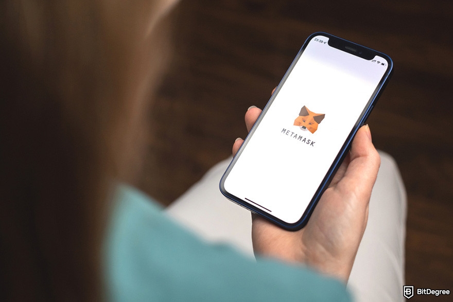 Is MetaMask safe: a person holding a smartphone displaying MetaMask's logo.