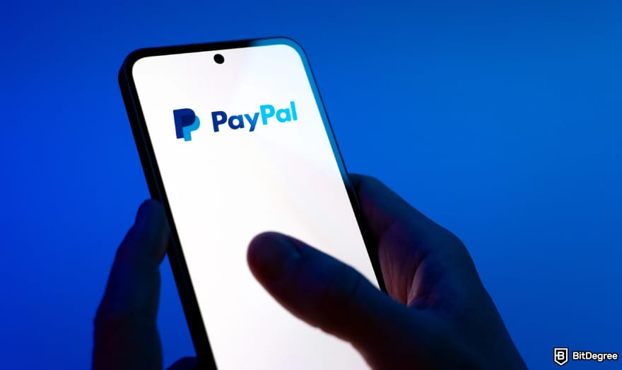Is PayPal available in India: person holding phone showing PayPal logo.