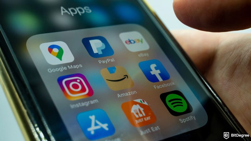 Is PayPal available in Philippines: close up hand holding a mobile phone with a screen of various applications.