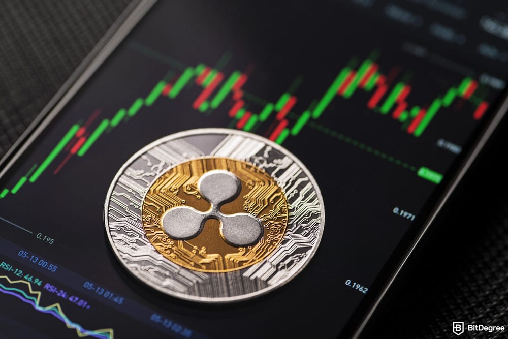 Is XRP dead: Ripple coin on top of a smartphone displaying a green chart.