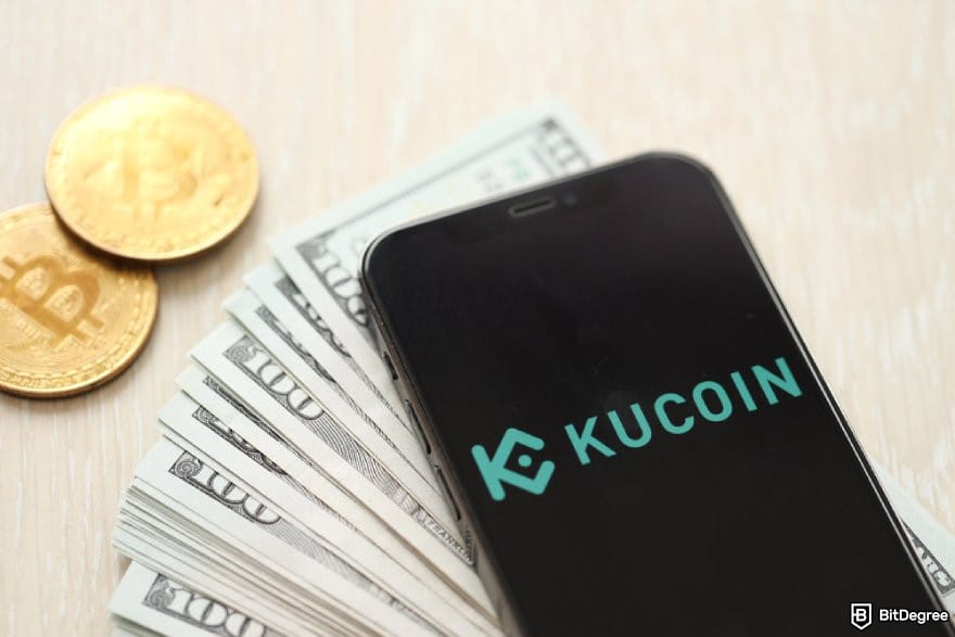 KuCoin review: a phone displaying KuCoin's logo, a stack of $100 bills, and BTC coins.