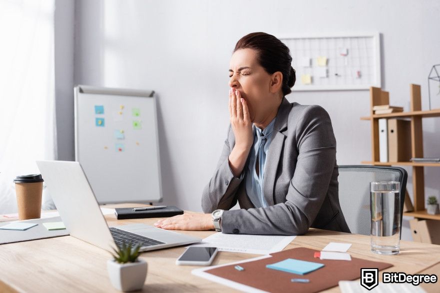 Looka review: A woman yawning while sitting at her table.