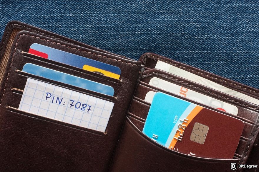 Managing multiple crypto wallets: a close-up of debit and credit cards and a paper containing pin in a wallet.