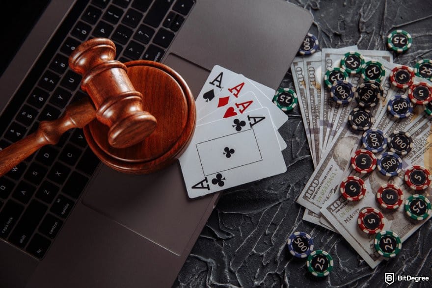 MetaWin Casino review: a gavel. poker chips, playing cards, and some $100 bills around a laptop.