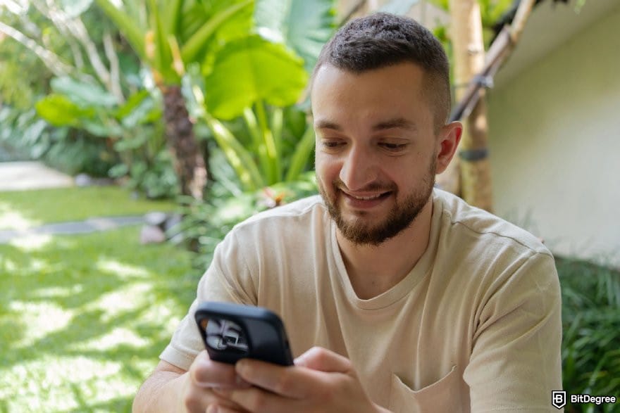 MetaWin Casino review: a person holding a mobile phone while smiling.