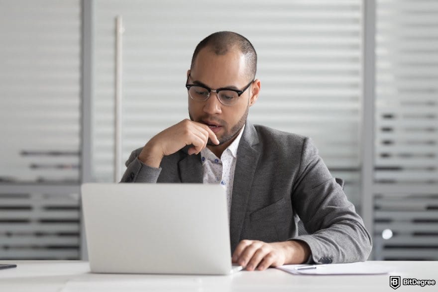 MEXC copy trading: a person looking at a laptop screen, thinking.