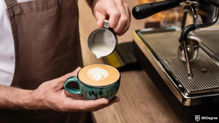 MIT data science certificate: barista in apron pouring milk to a coffee.