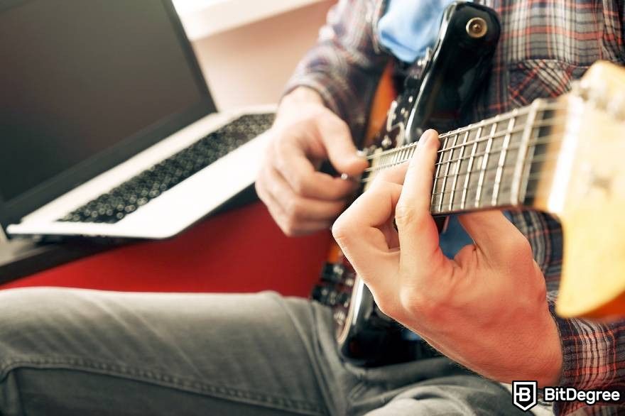 NFT Music: Musician playing guitar in front of laptop