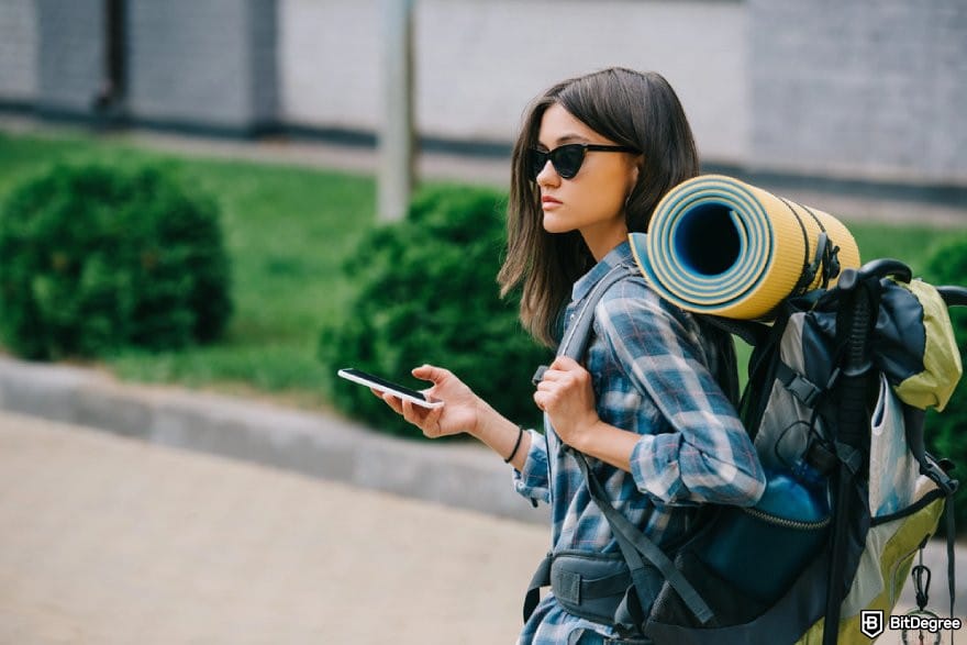 Ogvio review: a person carrying a travelling backpack holding a phone.