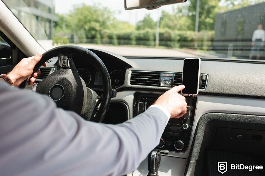 Otter.ai review: A man in a car trying to access his phone.