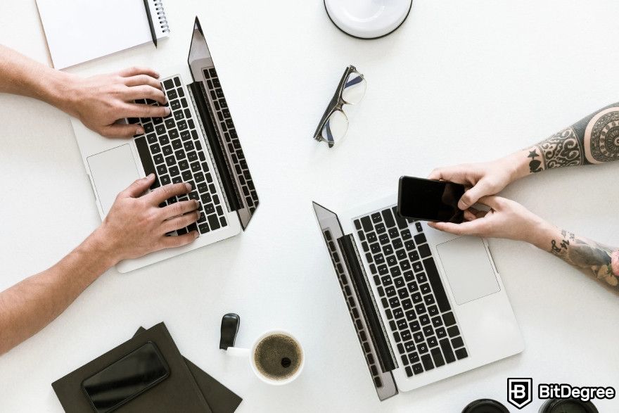 Otter.ai review: Two men sitting at a table with laptops.